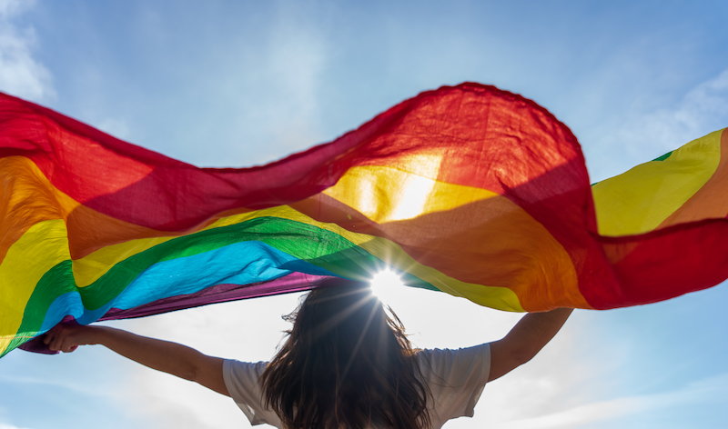 Women displaying pride flag to celebrate Pride Month